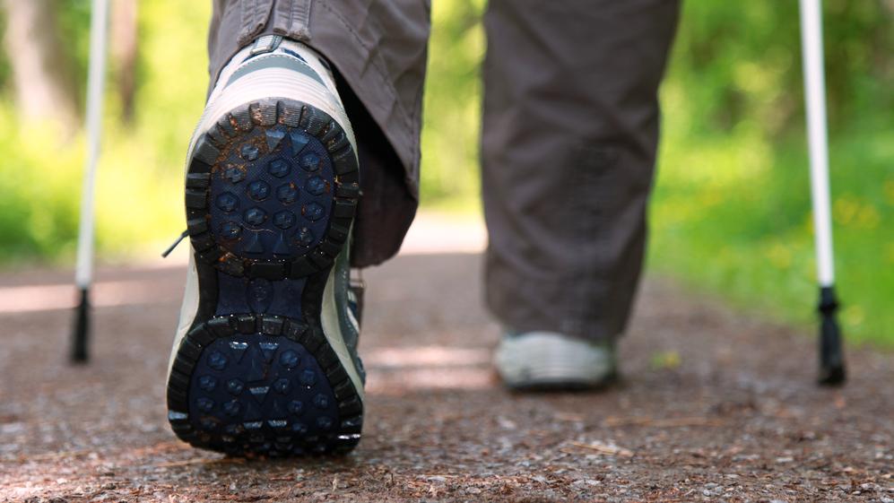 Nahaufnahme eines Wanderschuhs mit abgenutzter Sohle auf einem naturbelassenen Waldweg.